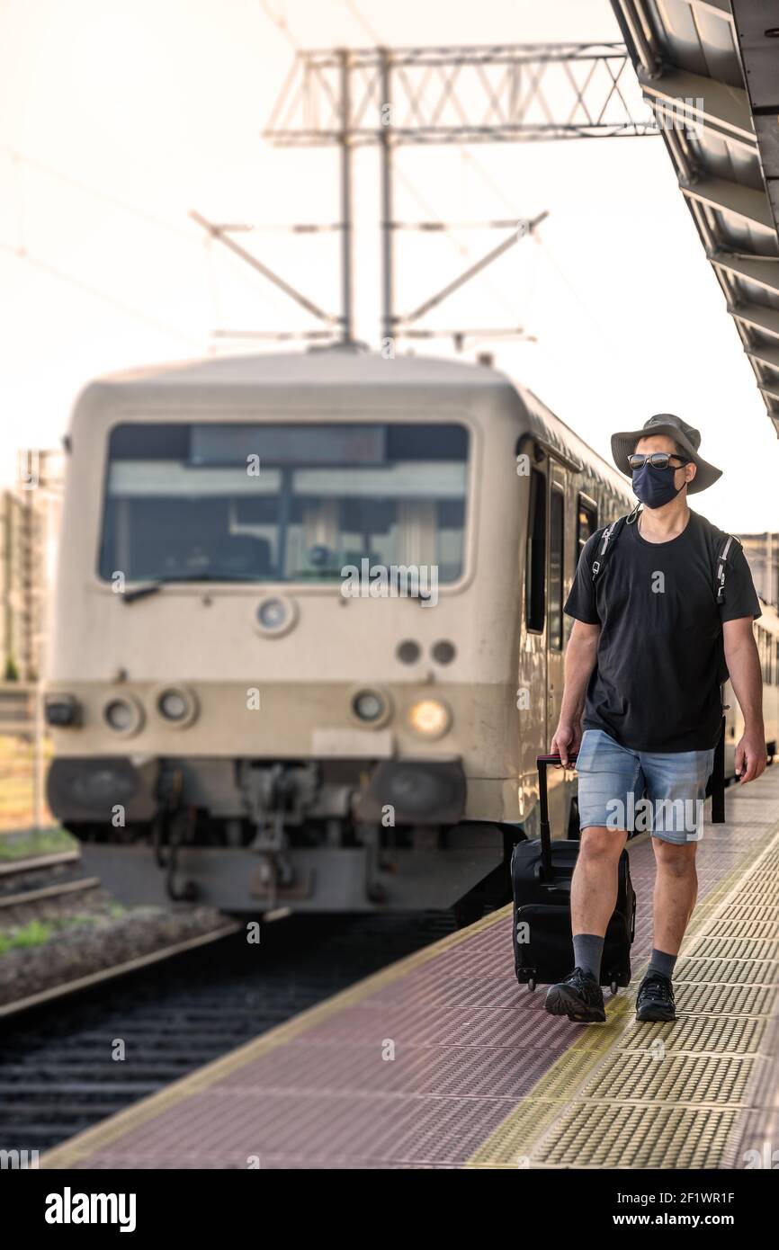 Man with a mask waiting for a train during Covid19 pandemic Stock Photo