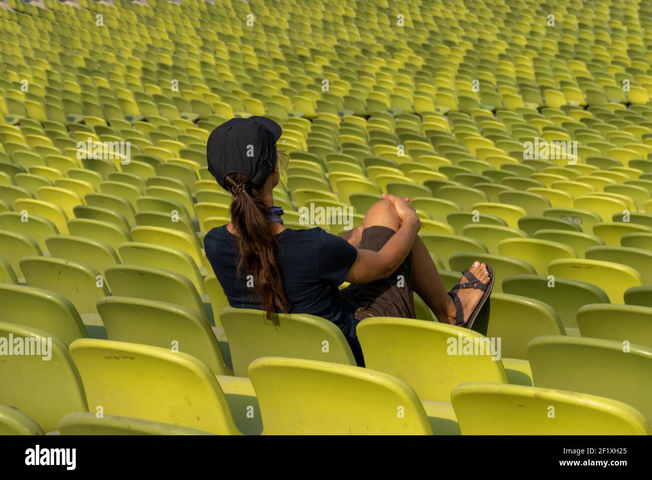 Stitting Single A single woman with long brown hair sitting alone in giant and empty ...