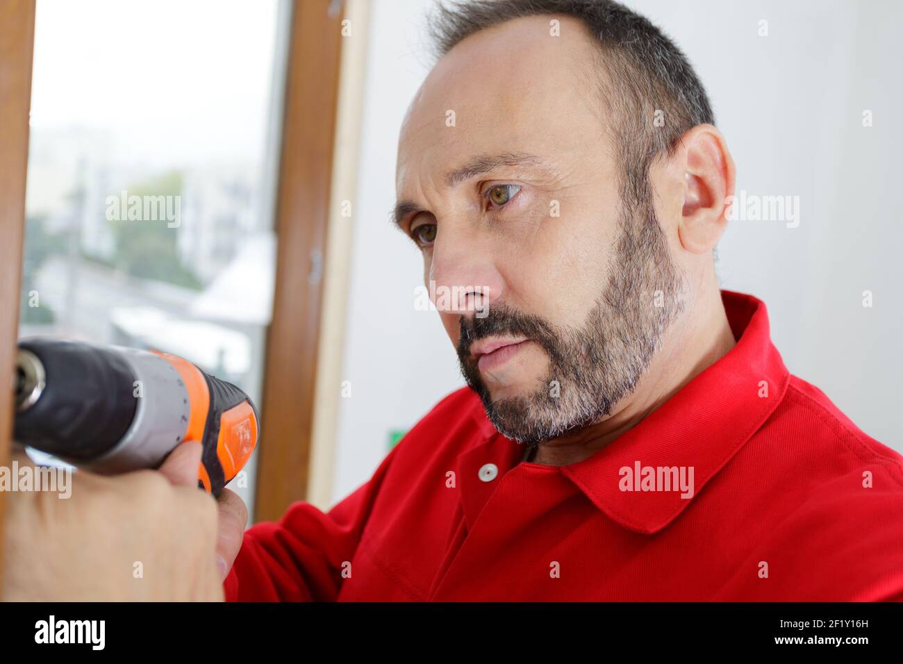 a bearded man using a drill Stock Photo