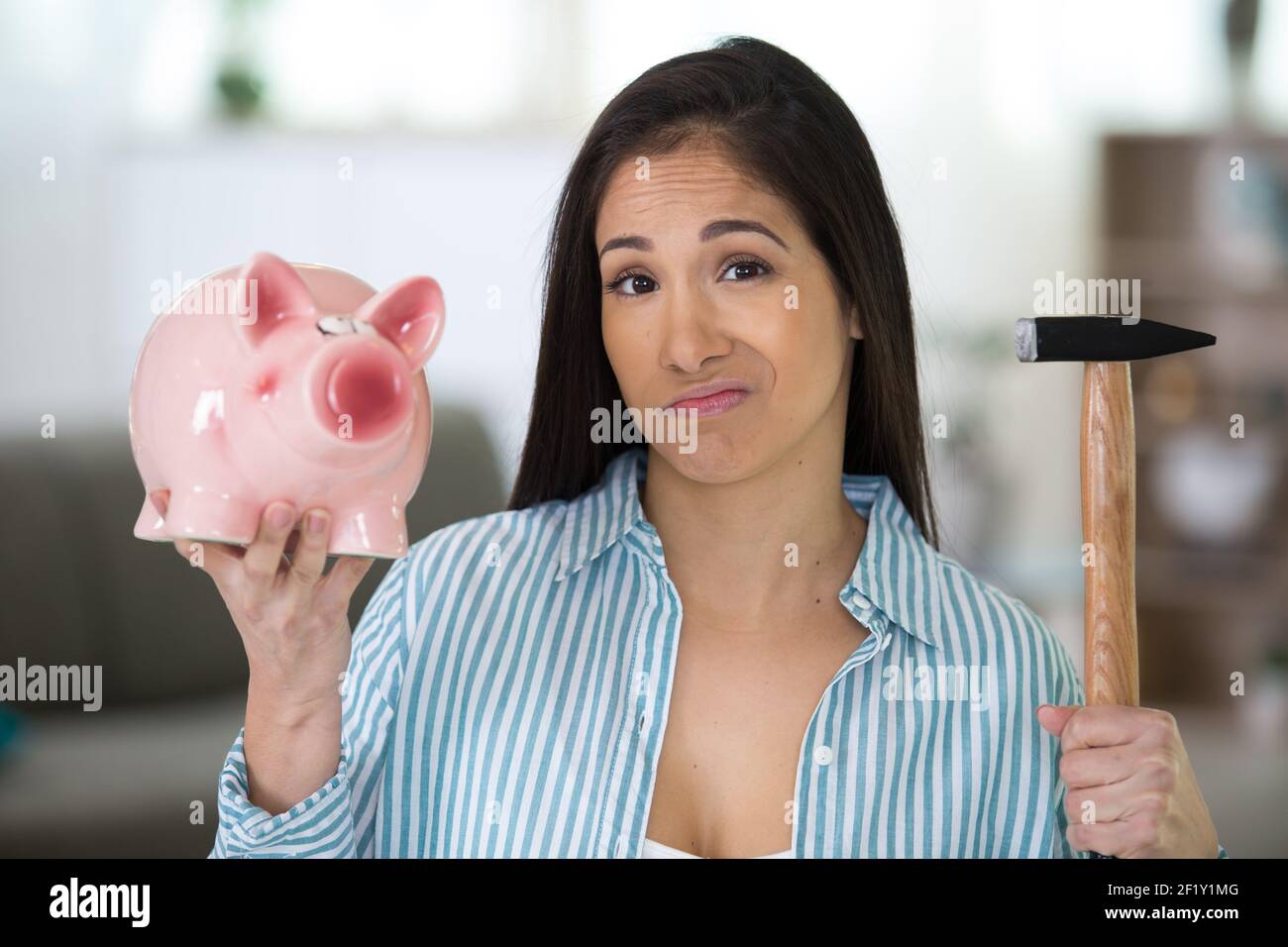 serious man breaking piggy bank with hammer Stock Photo - Alamy