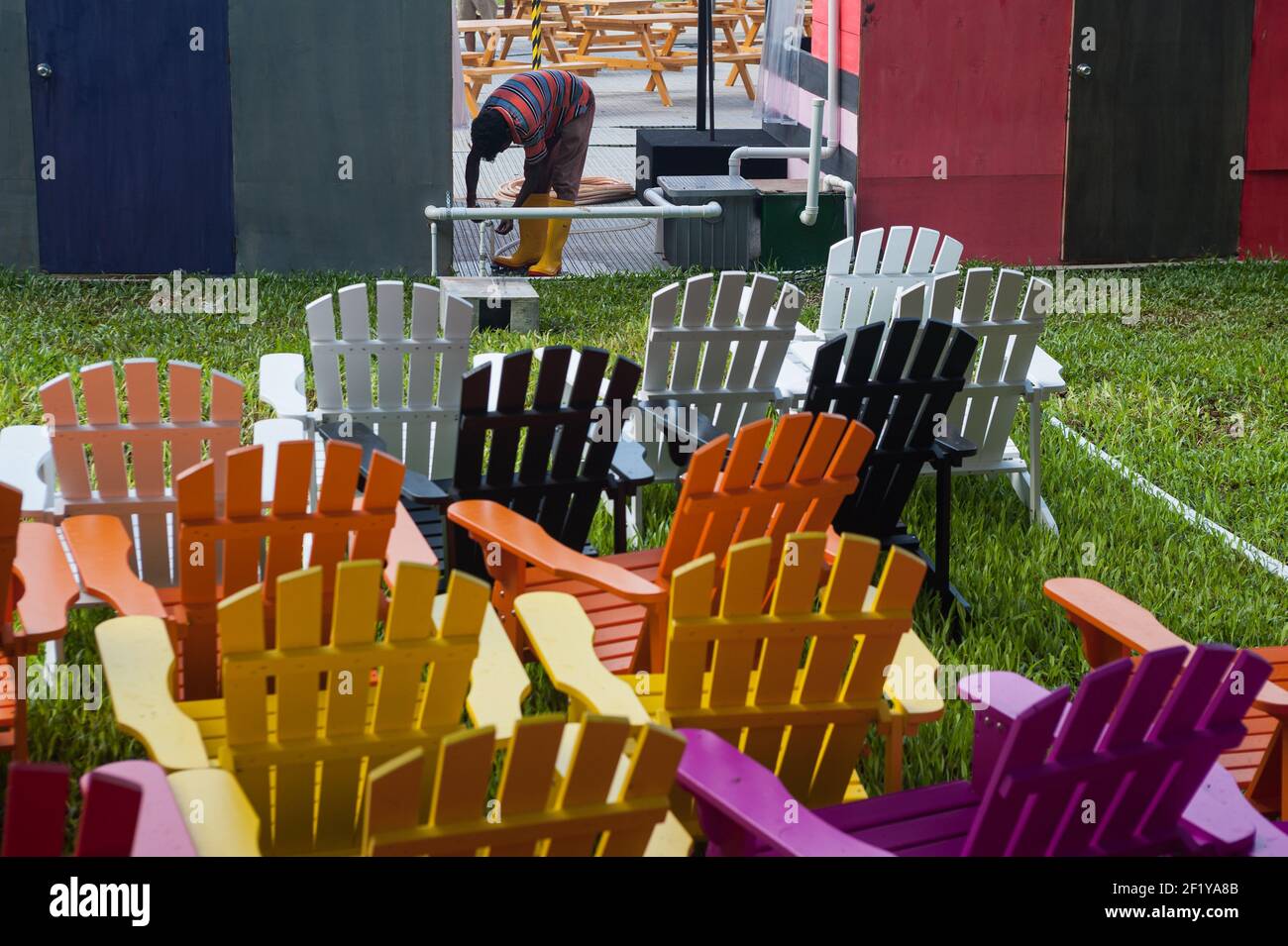 25.05.2017, Singapore, Republic of Singapore, Asia - A South Asian migrant worker goes about his duties with colourful chairs in the foreground. Stock Photo