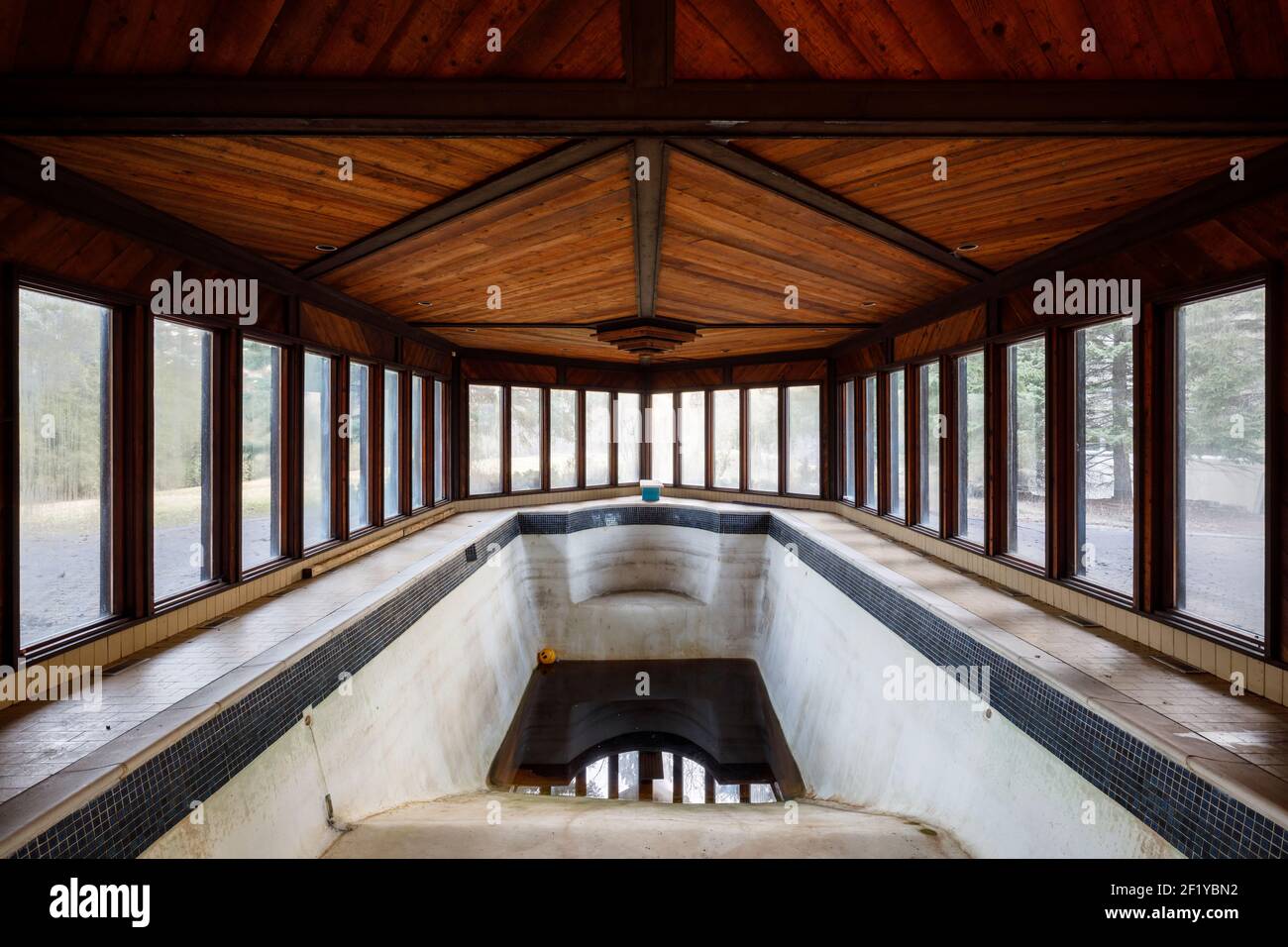 An indoor swimming pool filled with dirty water inside an abandoned mansion. Stock Photo