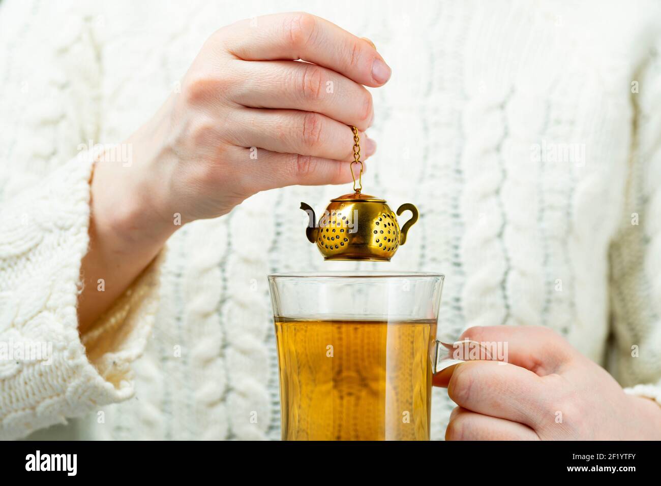 Vintage tea strainer. Woman brews tea with gold tea strainer in the