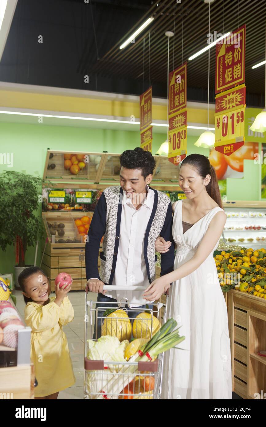 A happy family of three in the supermarket shopping Stock Photo
