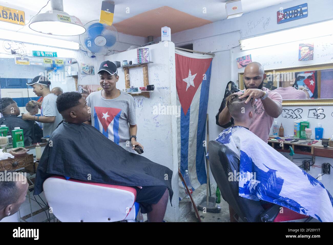 Cuba, Havana - Customers get their hair cut inside a barbershop Stock Photo