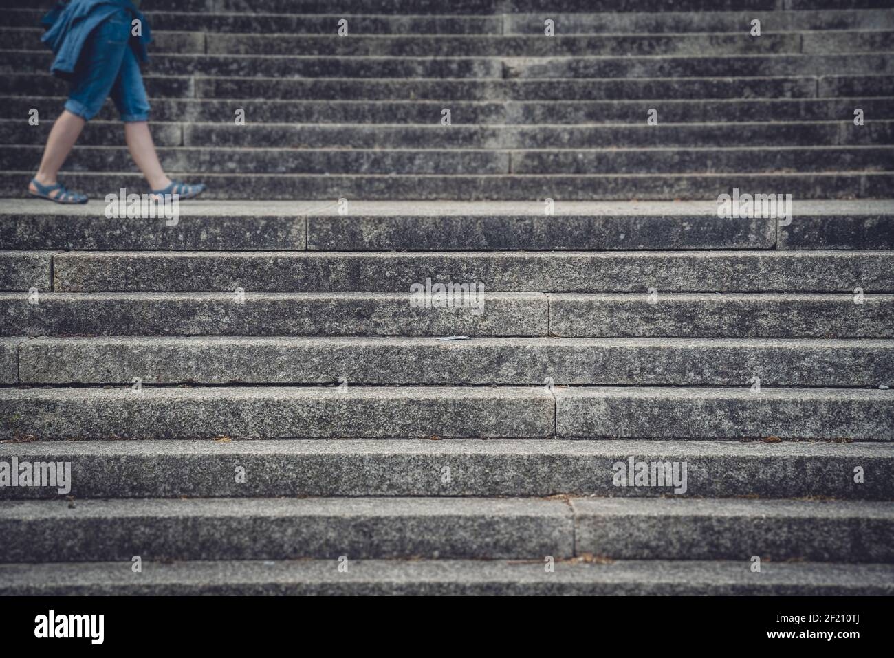 Legs of a woman walking between concrete stairs Stock Photo