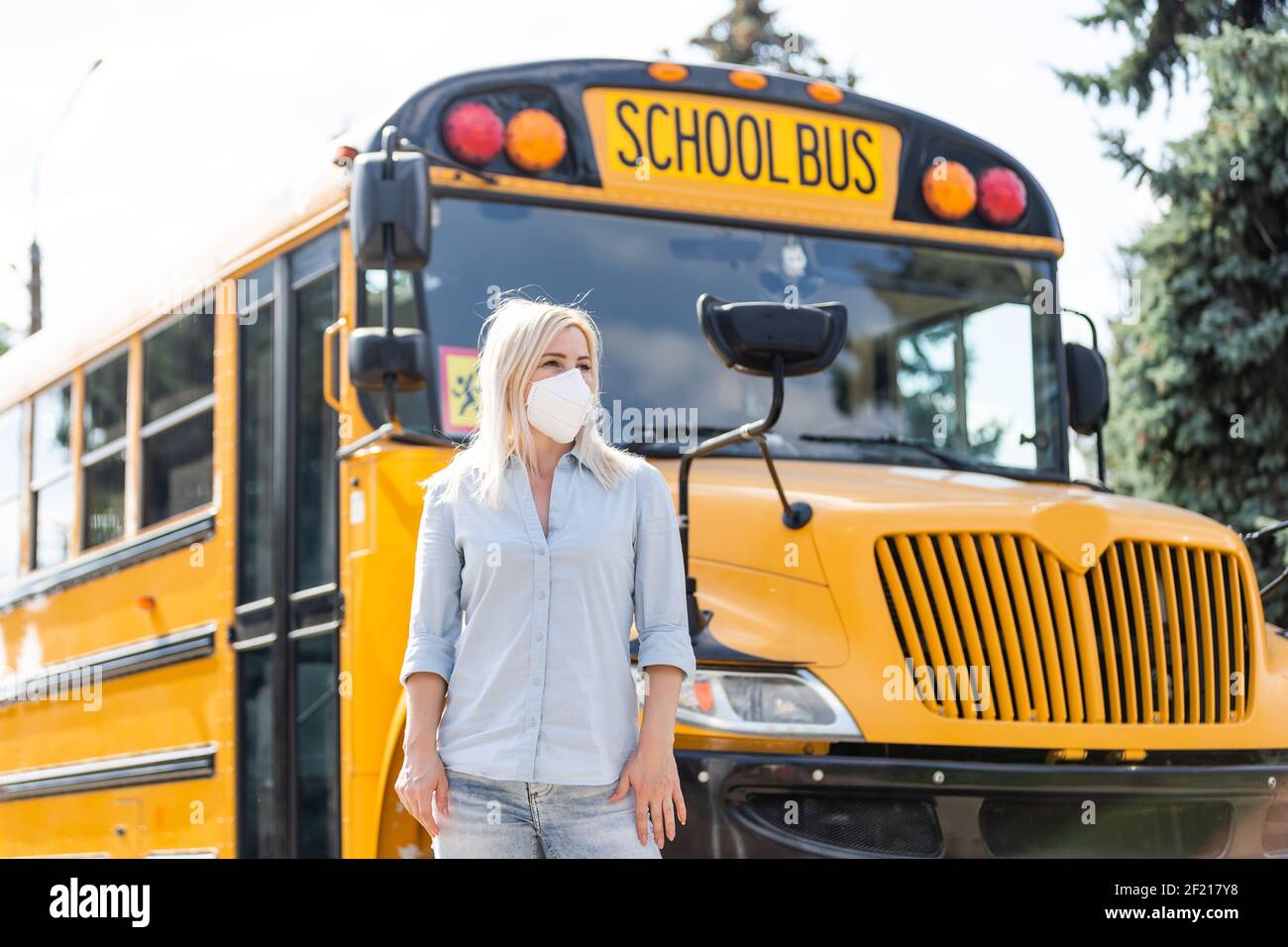 Portrait of beautiful female masked teacher near school bus Stock Photo ...