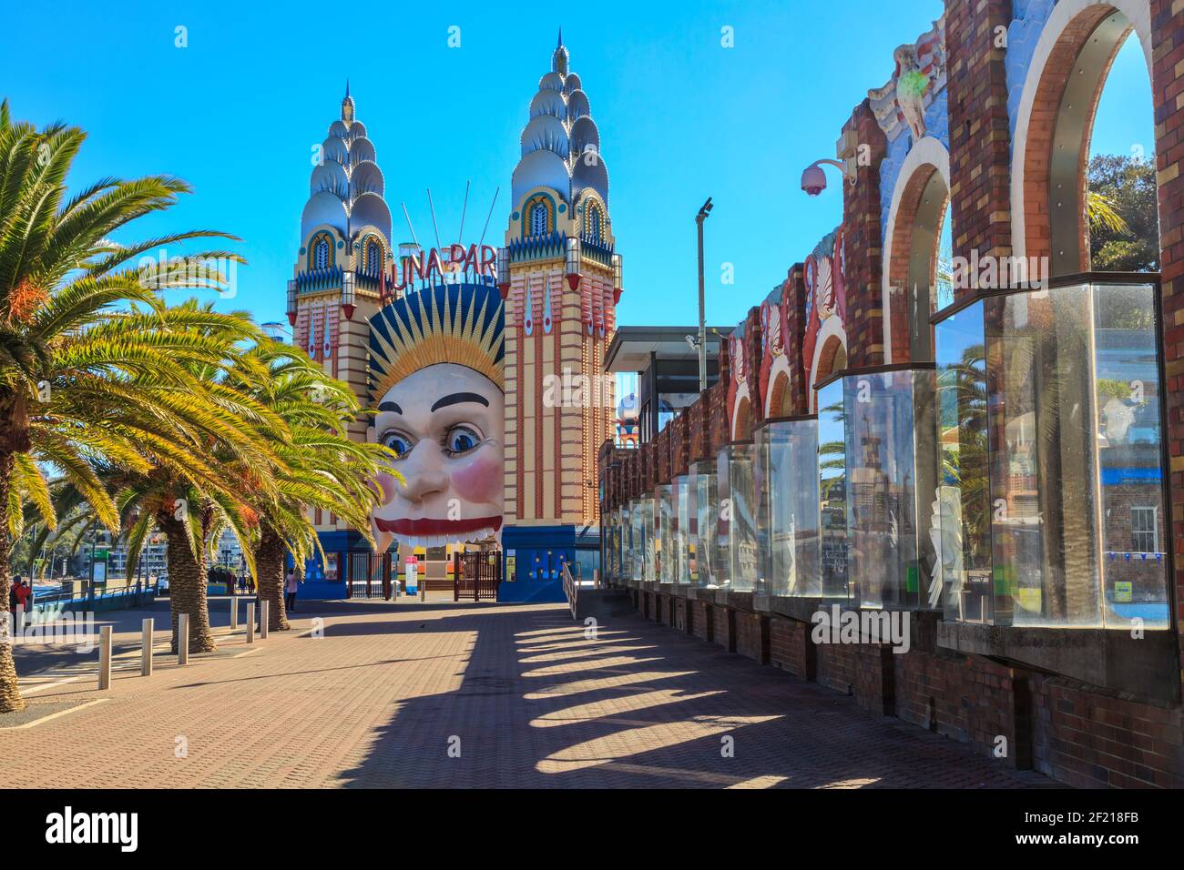 The smiling face entrance to Luna Park Sydney, an amusement park. To the right is the decorative wall of the North Sydney Olympic Pool Stock Photo