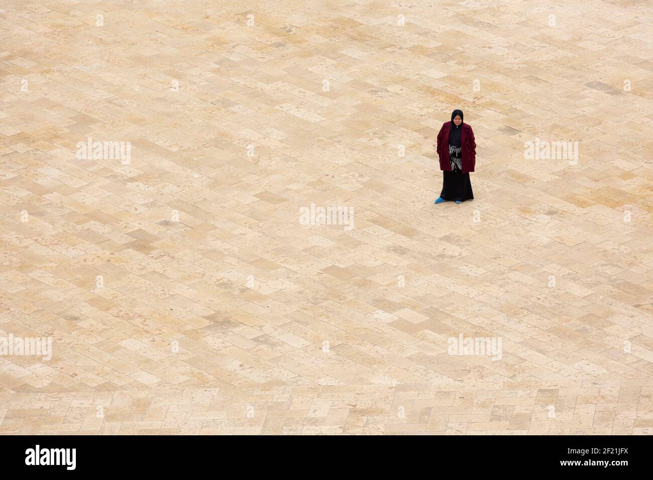 A local Egyptian woman standing in the expansive courtyard of the Mosque of Ibn Tulun, in Tolon, El-Sayeda Zainab, Cairo, Egypt Stock Photo
