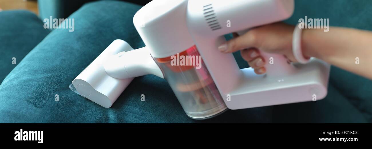 Use small vacuum cleaner to clean fabric on sofa. Stock Photo