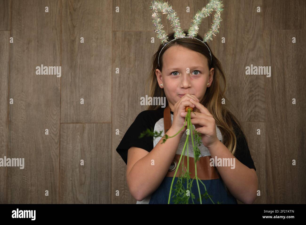 a girl with bunny ears nibbles on a carrot Stock Photo