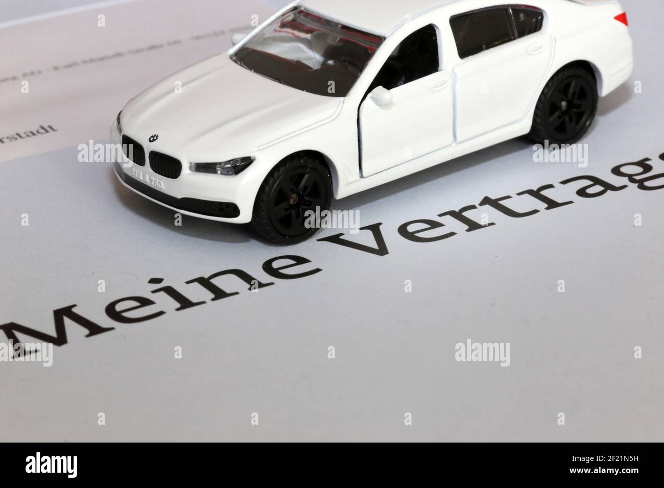 Symbol picture car insurance: Model car with contract documents (german) Stock Photo