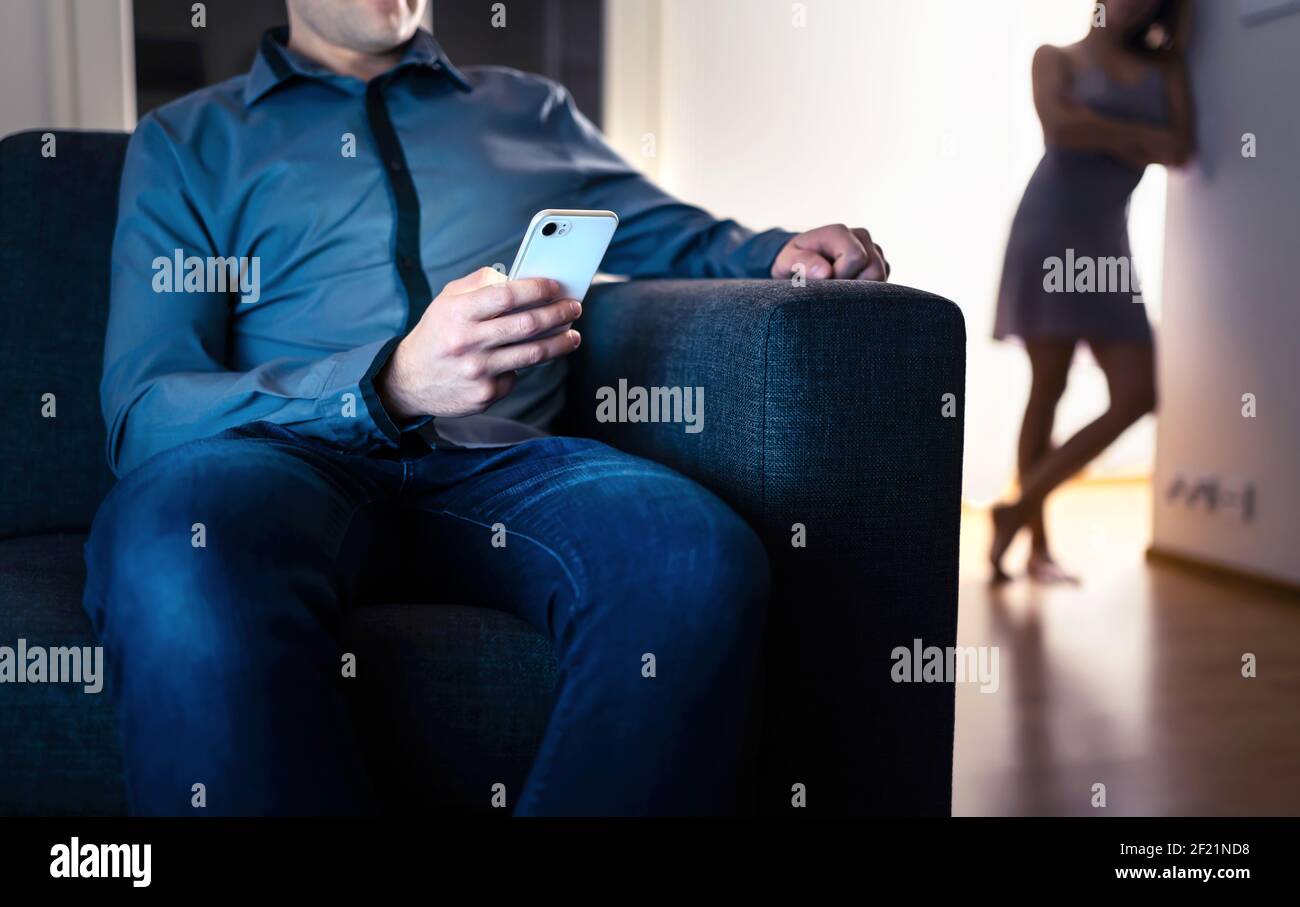 Jealous woman and cheating man with a phone. Infidelity, jealousy and betrayal. Cheater husband texting with mistress and secret lover. Stock Photo