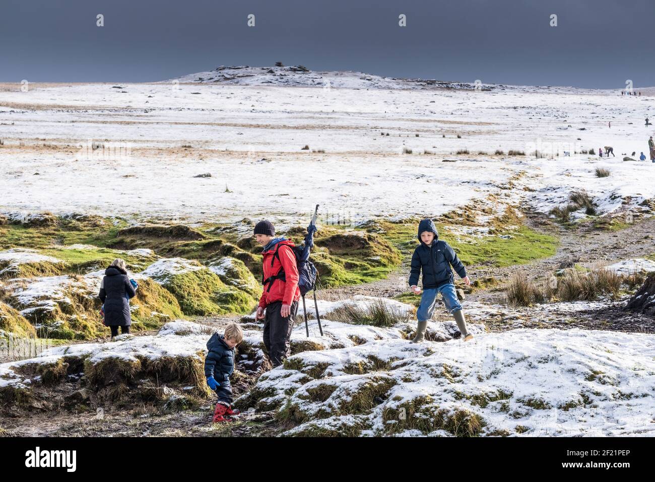 People enjoying themselves in the snow on the wild rugged Rough Tor on Bodmin Moor in Cornwall. Stock Photo
