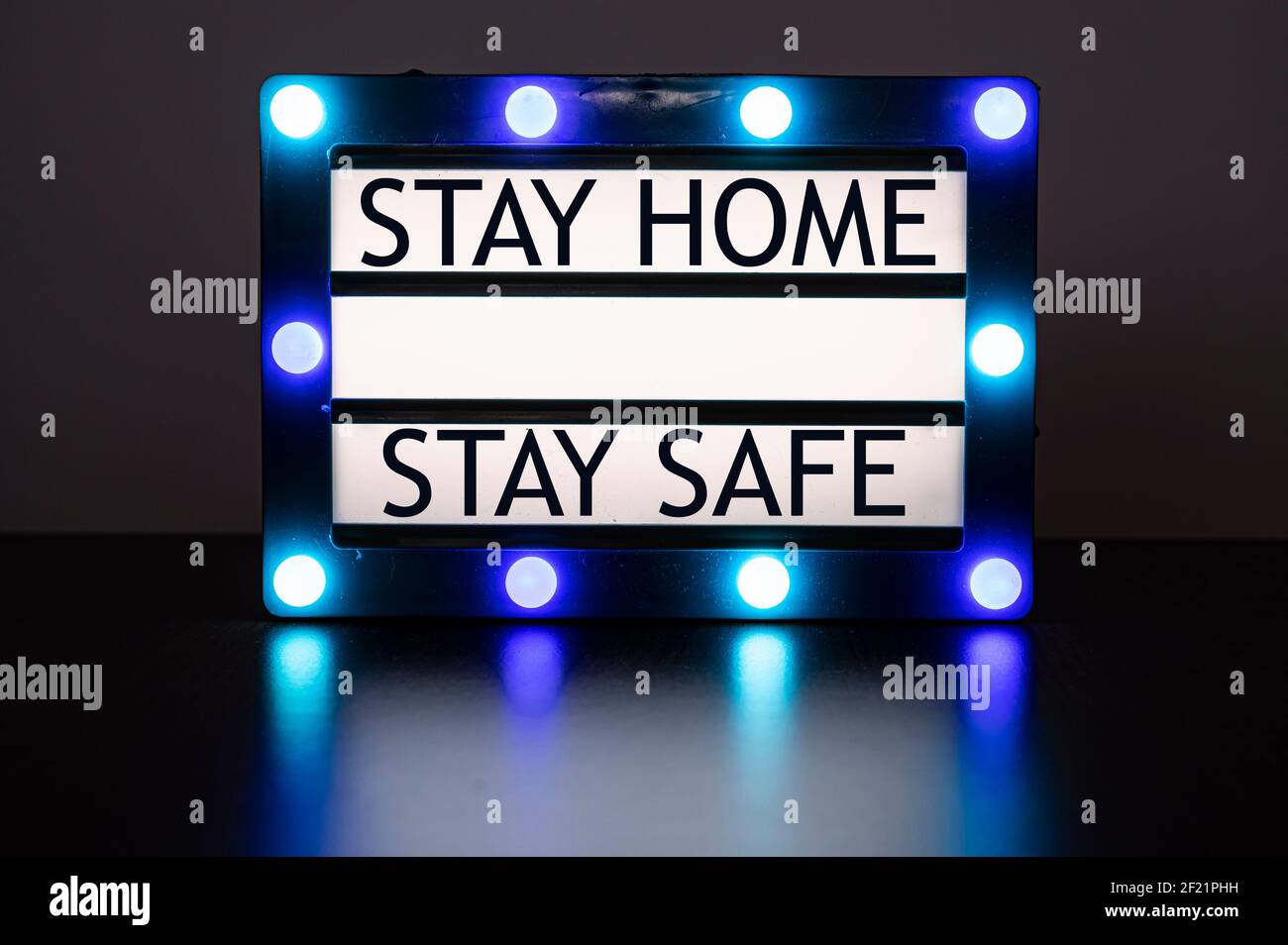 Lightbox with green and blue lights in dark room with words 'stay home, stay safe' Stock Photo