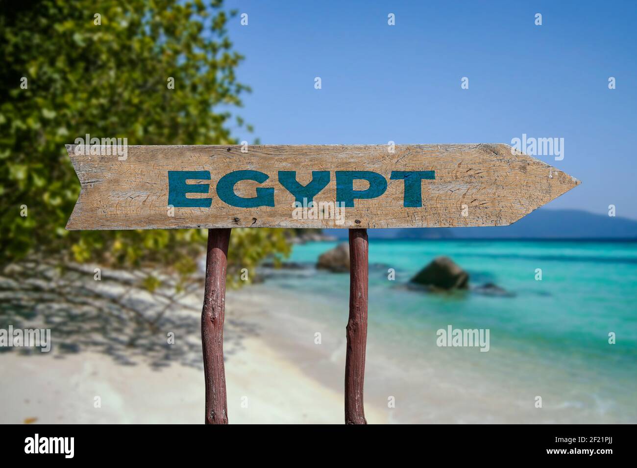 Egypt wooden arrow road sign against tropical beach with white sand and turquoise water background. Travel to Egypt  concept. Stock Photo