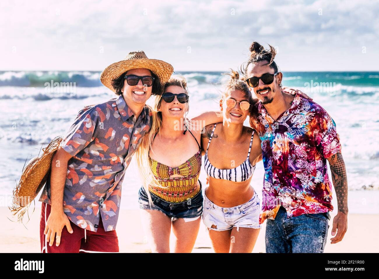 Group of young people friends have fun and enjoy friendship at the beach in summer holiday vacation smiling and laughing - blue ocean and sky backgrou Stock Photo