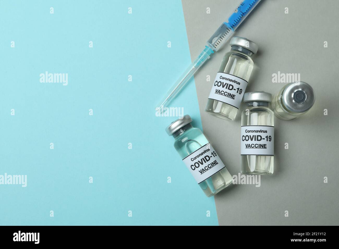Vials of Covid - 19 vaccine and syringe on two tone background Stock ...