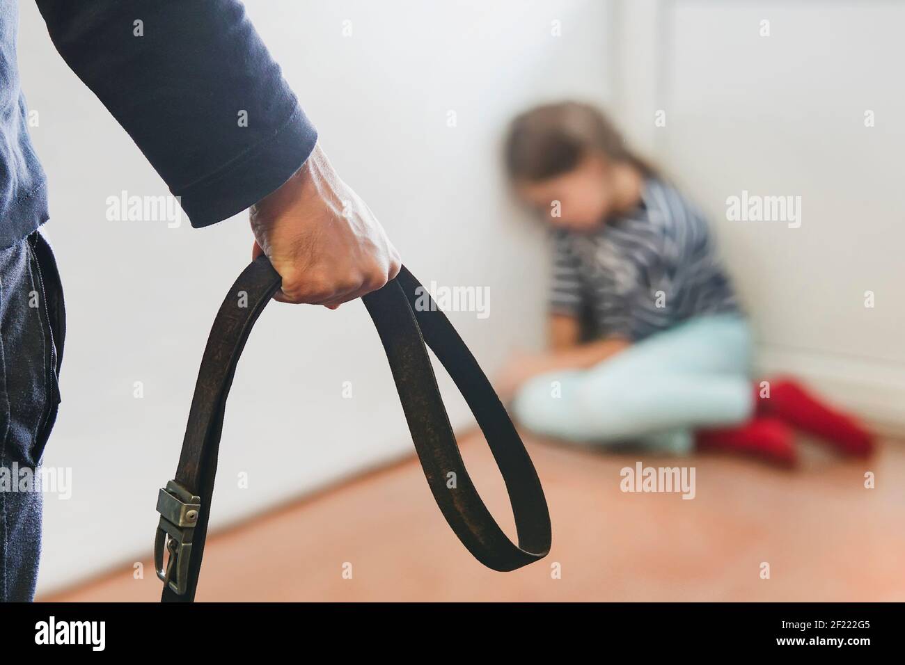 The girl is sitting in the corner hiding from her abusive stepfather. The concept of raising children through domestic violence. Punishment for a crim Stock Photo