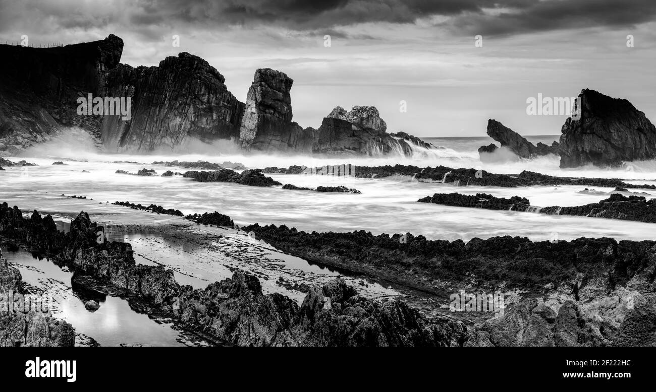 Rocky and wild coast with stormy waves hitting the shore Stock Photo