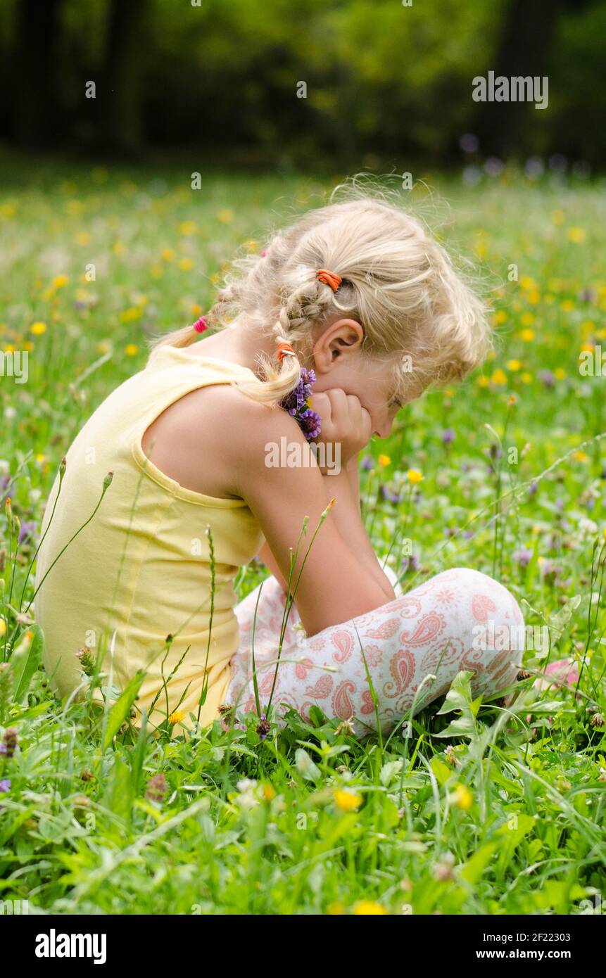 beautiful blond girl sitting on meadow Stock Photo - Alamy