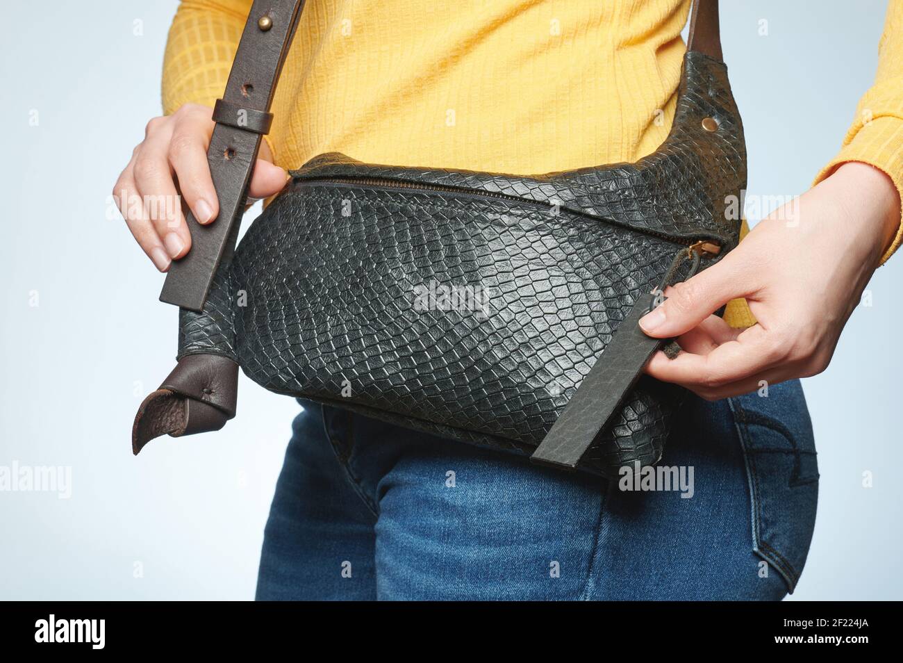 Woman hold black leather handbag on blue casual jeans isolated Stock Photo