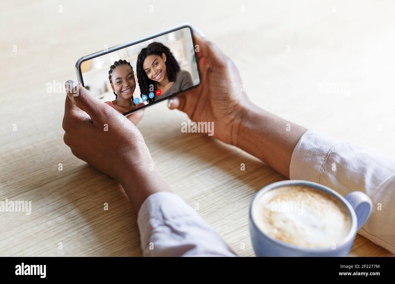 Young black lady with coffee speaking to her friends remotely, using smartphone to talk to family online, closeup Stock Photo