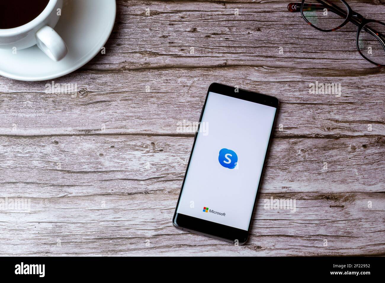 A mobile phone or cell phone laid on a wooden table or desk with the Skype app open Stock Photo
