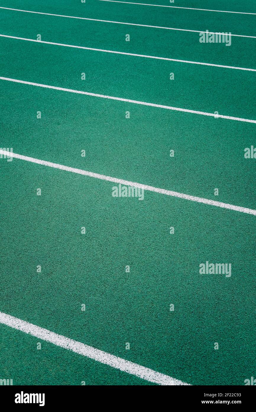 White lines marking lanes on a green athletics track running diagonally across the image Stock Photo