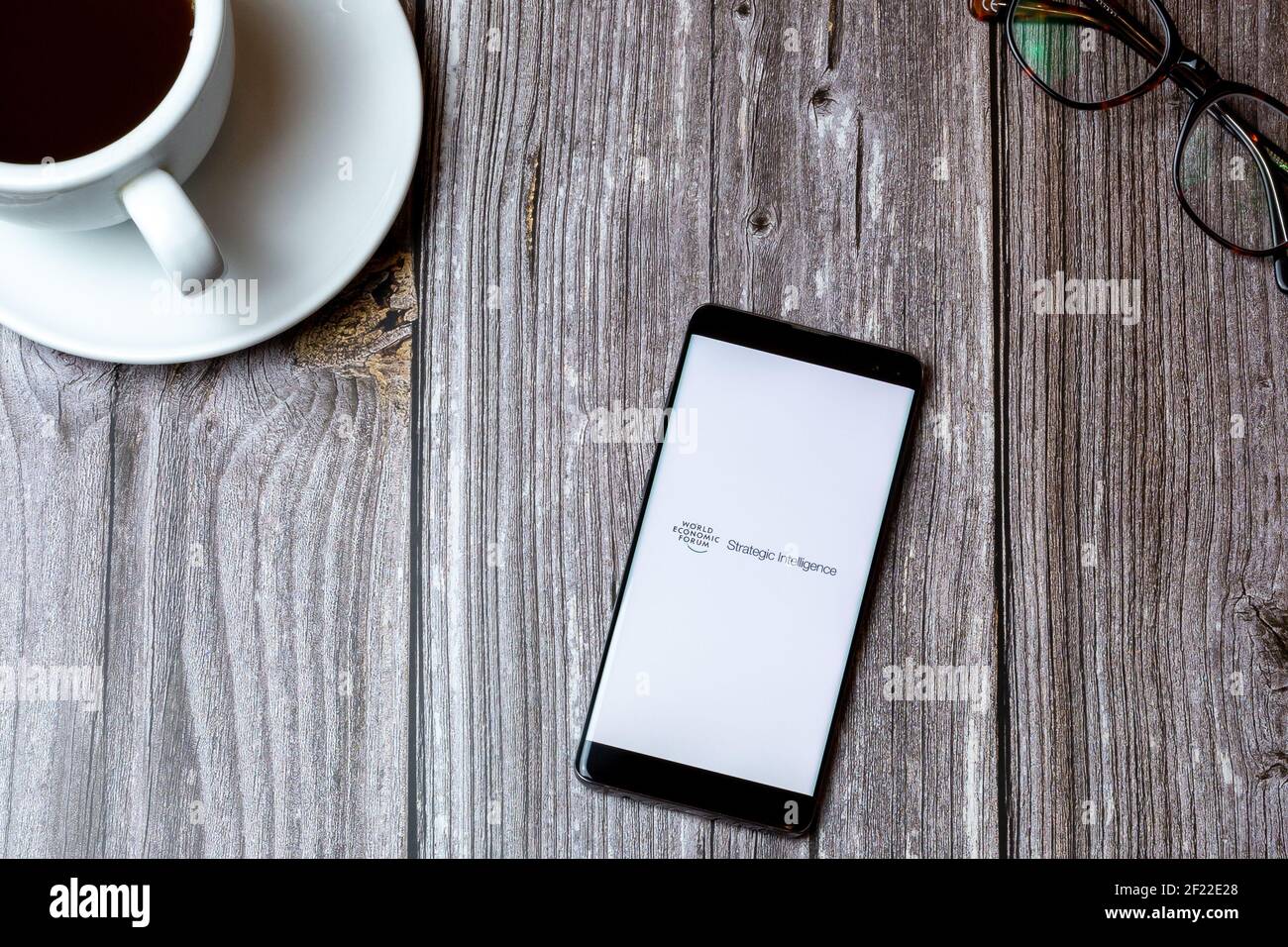 A mobile phone or cell phone laid on a wooden table with the World economic forum app open on screen Stock Photo