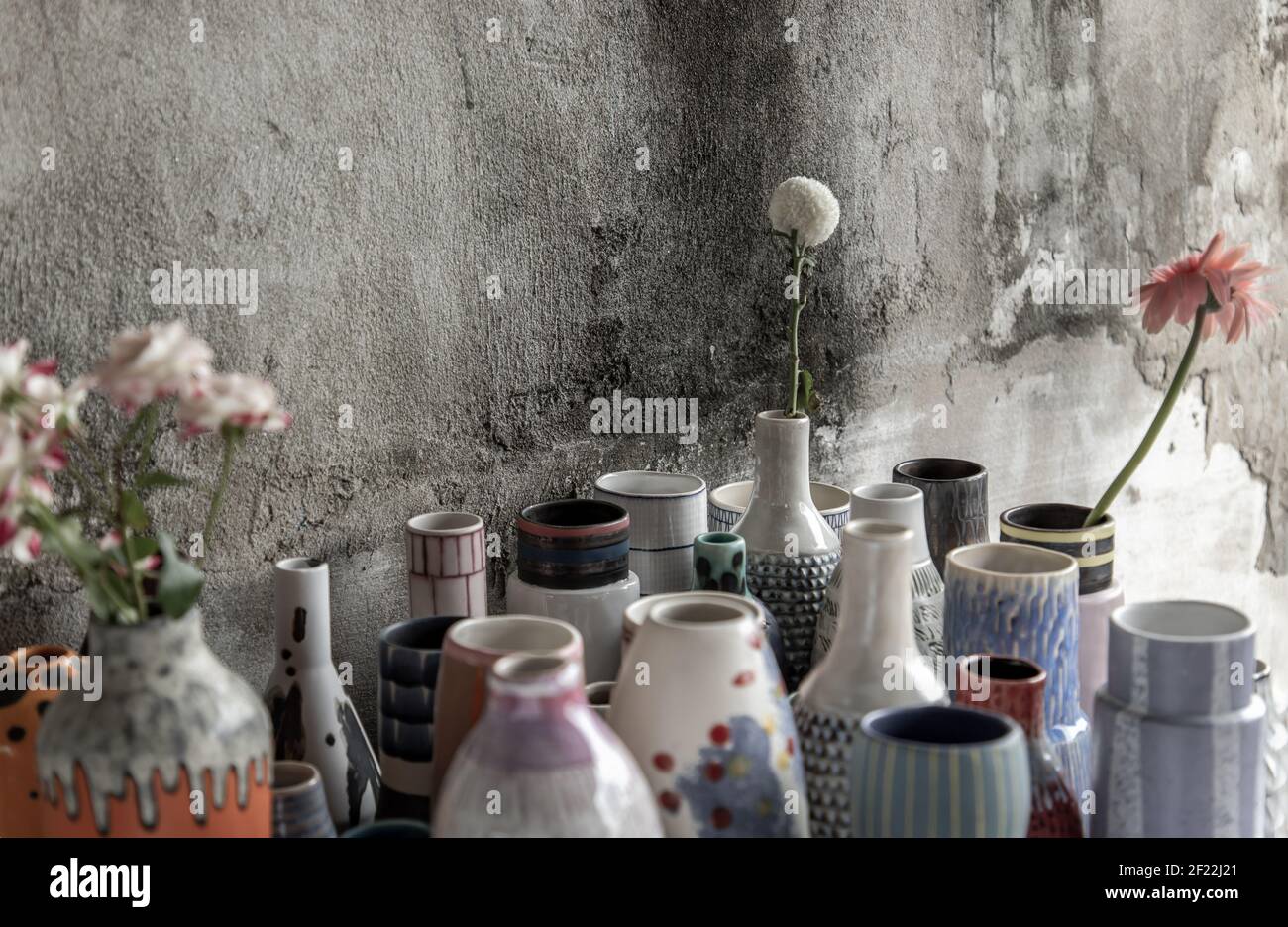 Bouquet of flowers in Handmade Assorted Many Different Ceramic Vases with old cement wall. Home decor. Selective focus. Stock Photo