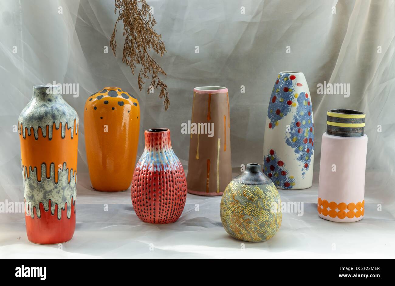 Handmade Assorted Many Different Ceramic Vases on Calico textured table cloth with old cement wall. Home decor. Selective focus. Stock Photo