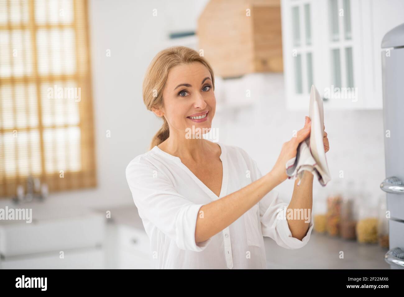 Blonde cute housewife holding a plate in her hands Stock Photo
