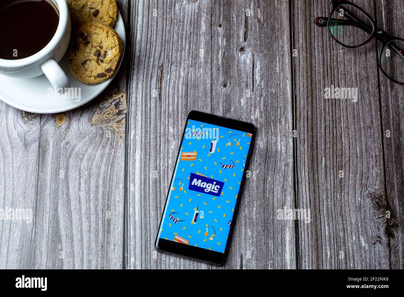 A mobile phone or cell phone laid on a wooden table with the Magic radio app open on screen Stock Photo