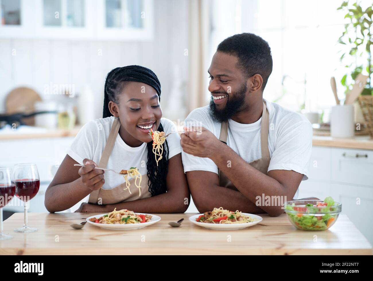 African American Lovers Eating Spaghetti And Drinking Red Wine In Kitchen Stock Photo