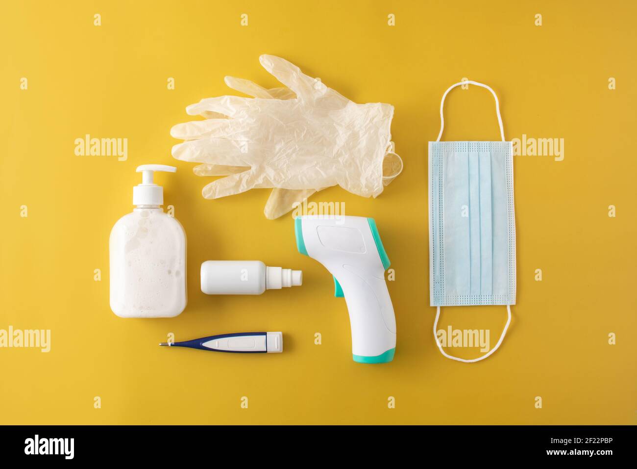 Medical gloves,disinfectant, thermometer, hand sanitizer and surgical mask on yellow background Stock Photo