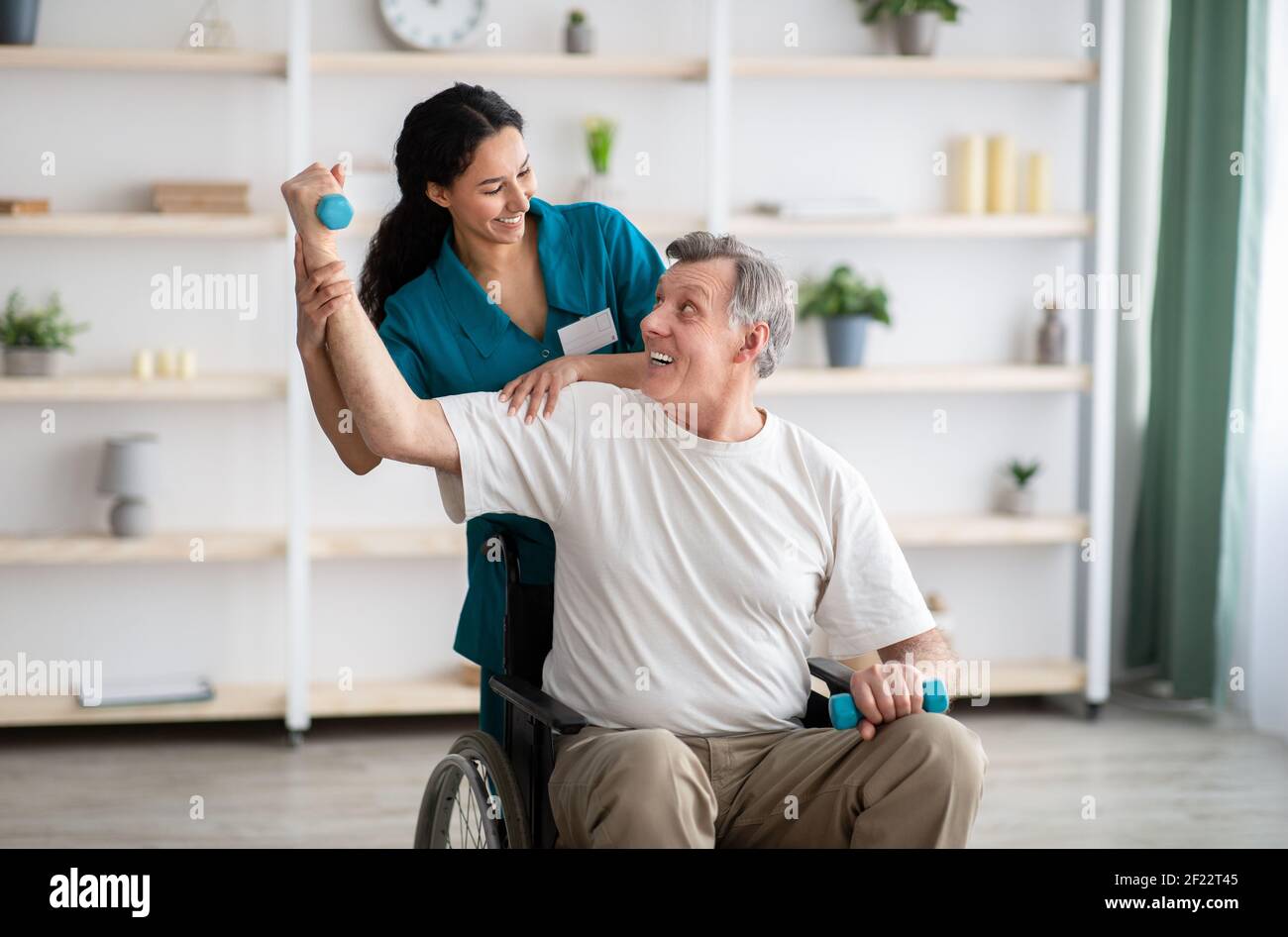 Rehabilitation of disabled people. Young physiotherapist helping senior
