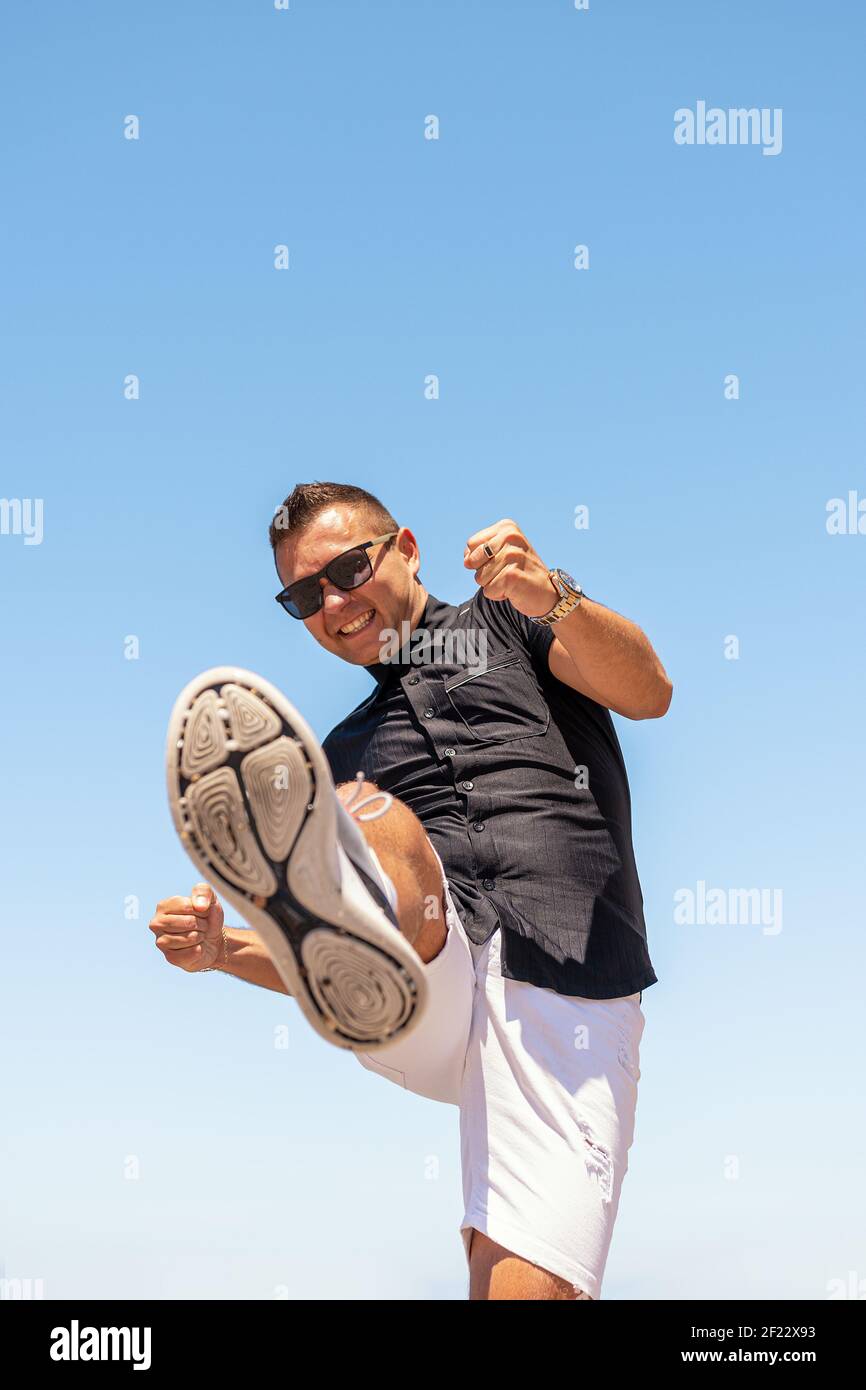 Young man in a black shirt kicks towards the camera. Stock Photo