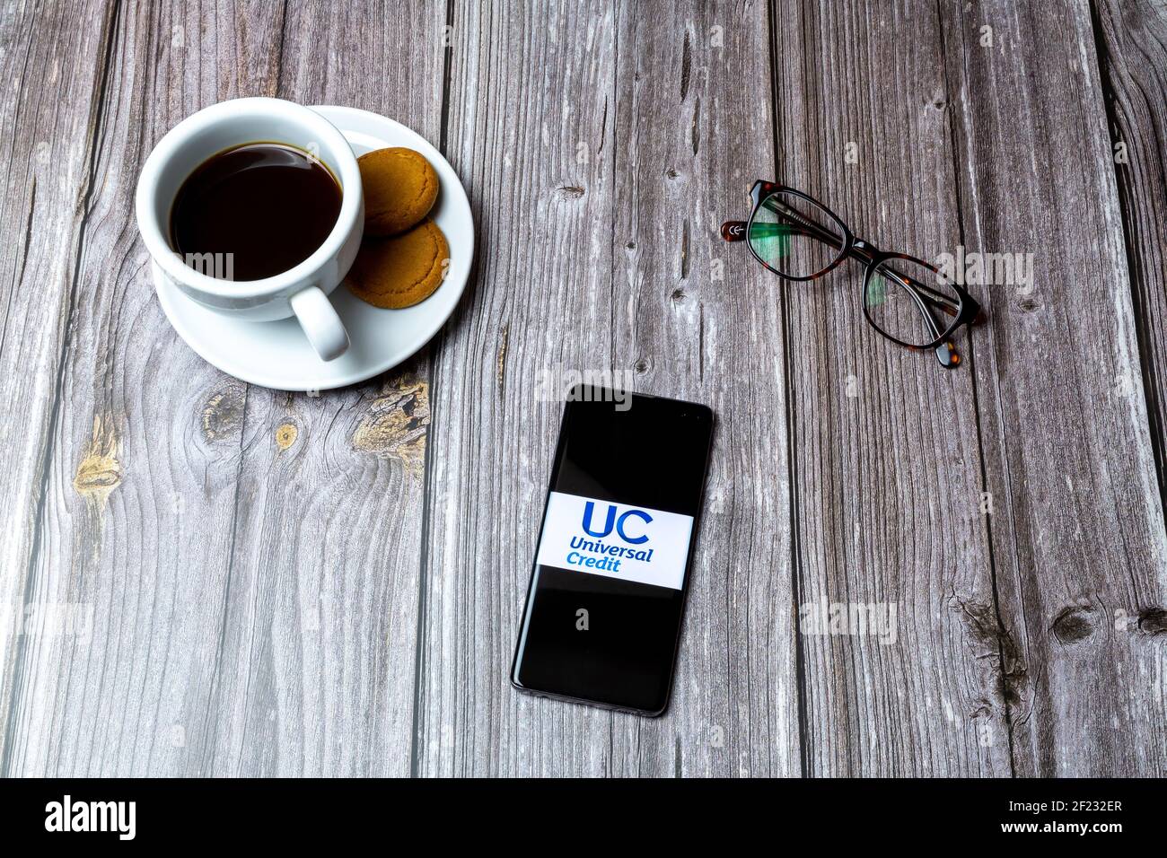 A Mobile phone or cell phone laid on a wooden table with the Universal Credit app open on screen Stock Photo