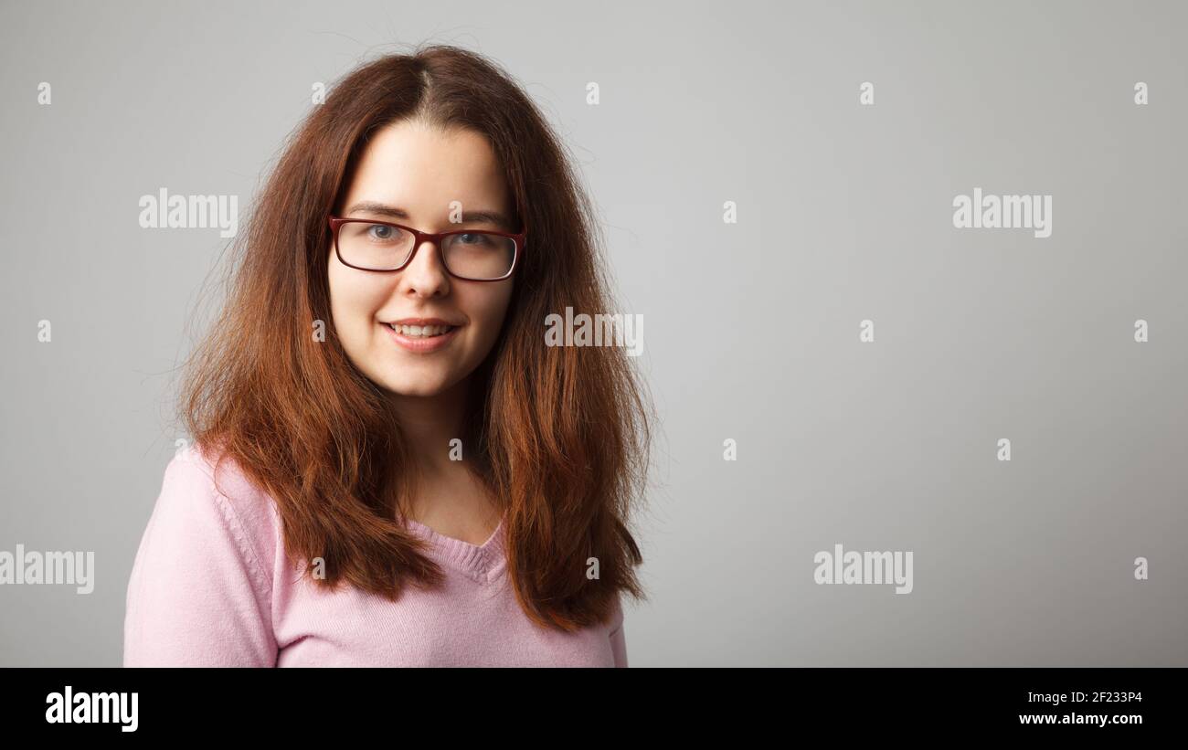 Portrait of young red-haired woman wearing glasses. Head and shoulders portrait. Stock Photo