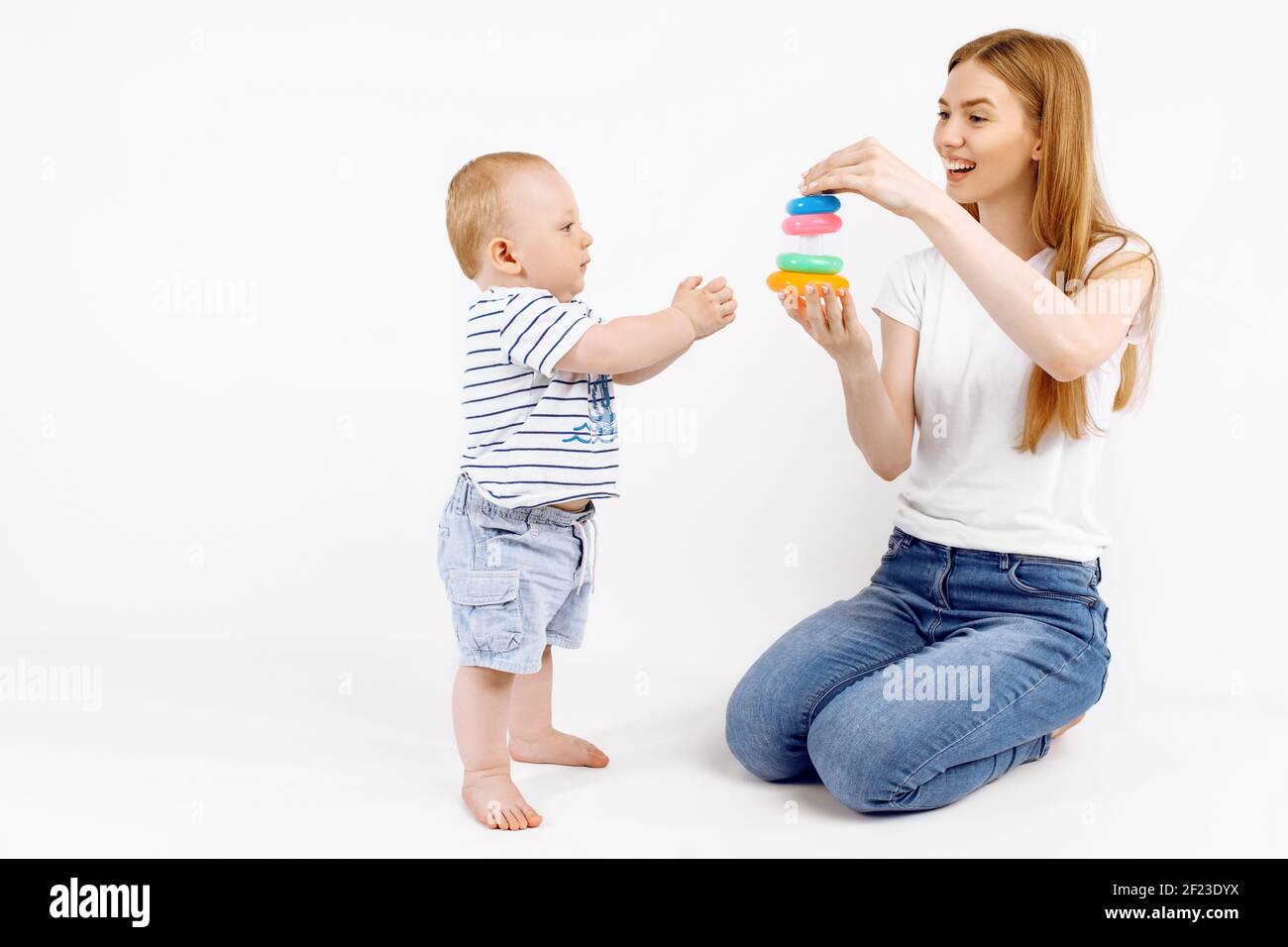Baby with mom playing with colorful toys, on an isolated white background, Early development Stock Photo