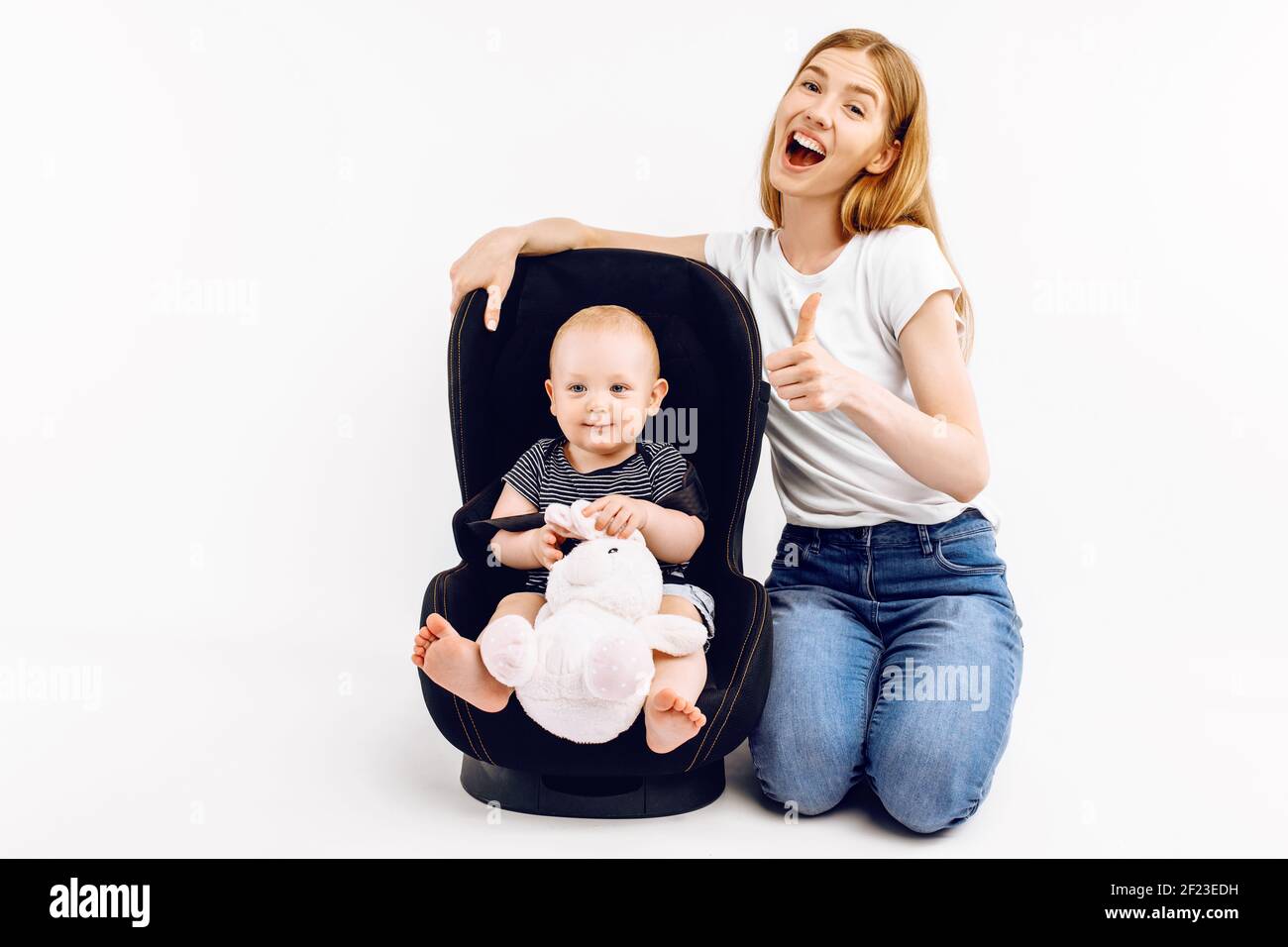 Baby in baby car seat, with mom on isolated white background Stock Photo