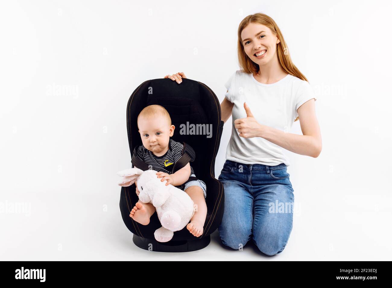 Baby in baby car seat, with mom on isolated white background Stock Photo