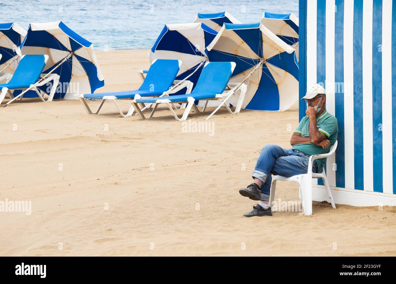 Las Palmas, Gran Canaria, Canary Islands, Spain. 10th March, 2021. A man hiring sunloungers takes a siesta on a quiet city beach in Las Palmas on Gran Canaria; a popular destination for many British holidaymakers. A glimmer of hope for the beleaguered tourism dependent Canary Islands economy as Covid vaccine passports are being considered by Spain in an effort to reboot tourism in the country. Credit: Alan Dawson/Alamy Live News. Stock Photo