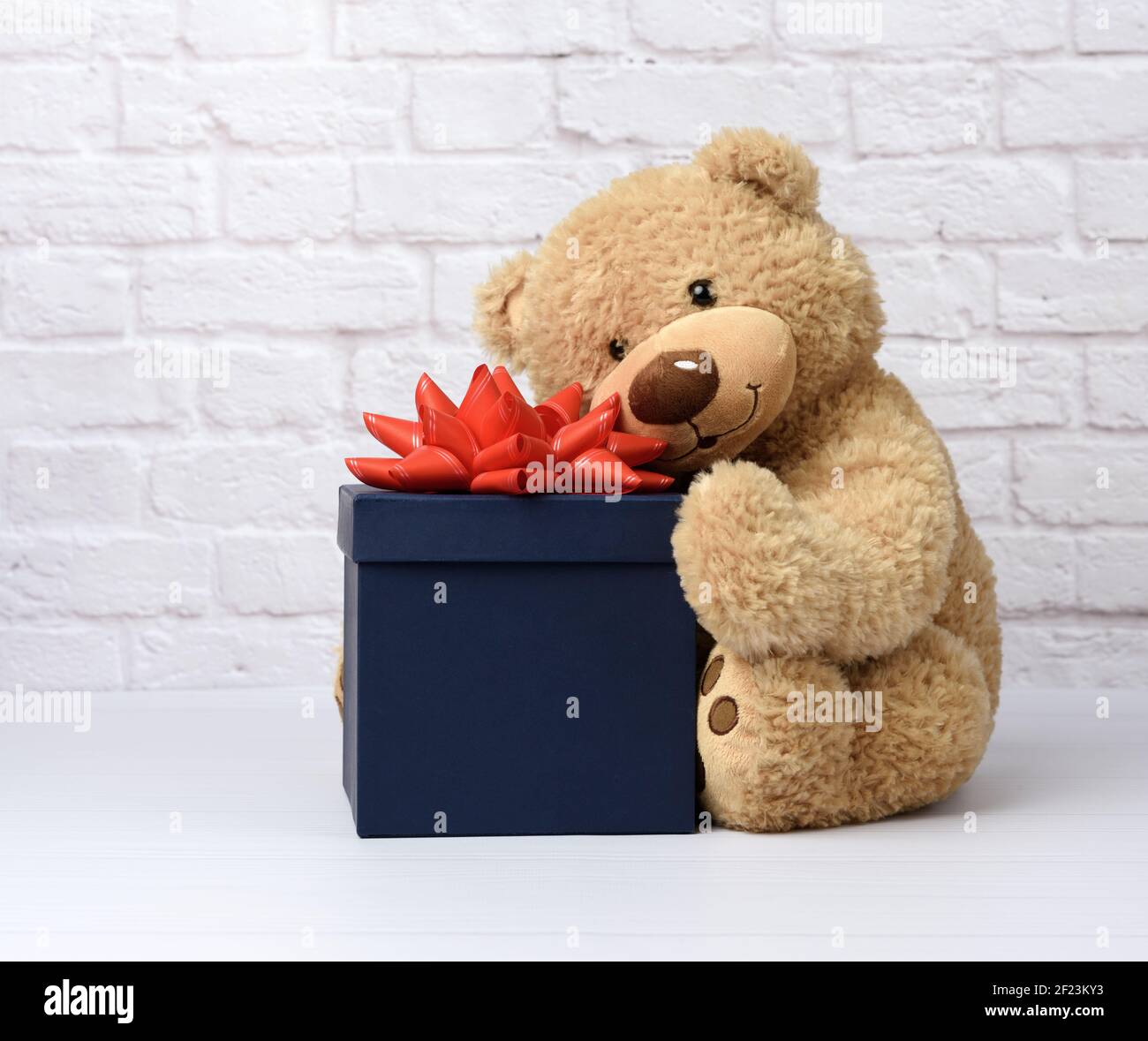 Big teddy bear and blue square cardboard box with red bow Stock Photo ...