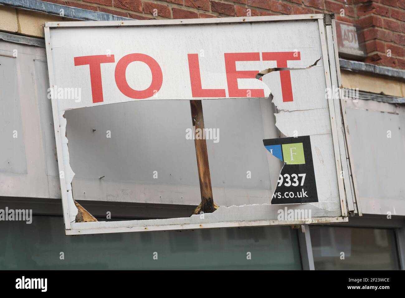 Damaged To Let sign over an empty retail shop premises in UK Stock Photo