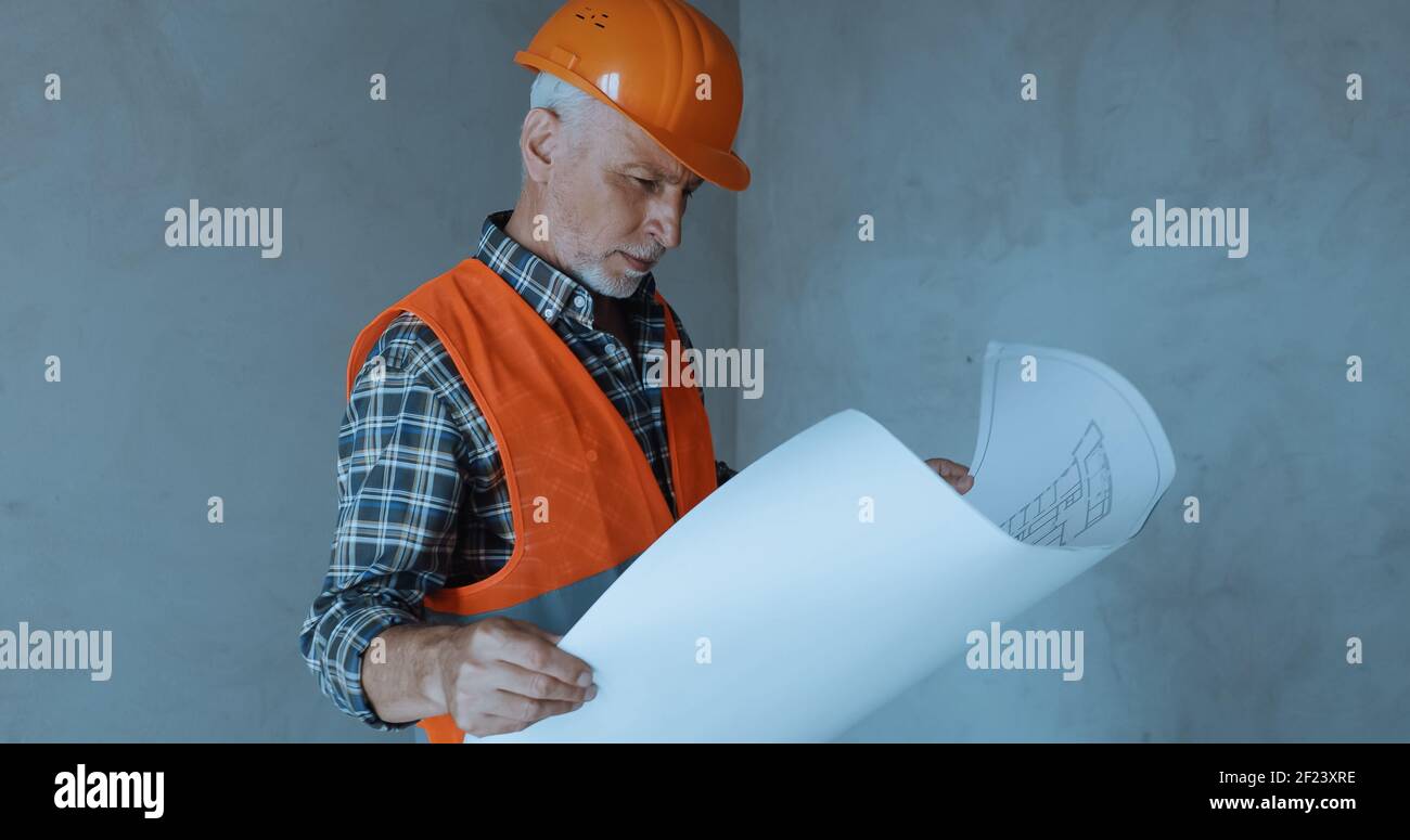 happy builder looking at blueprint on construction site Stock Photo - Alamy