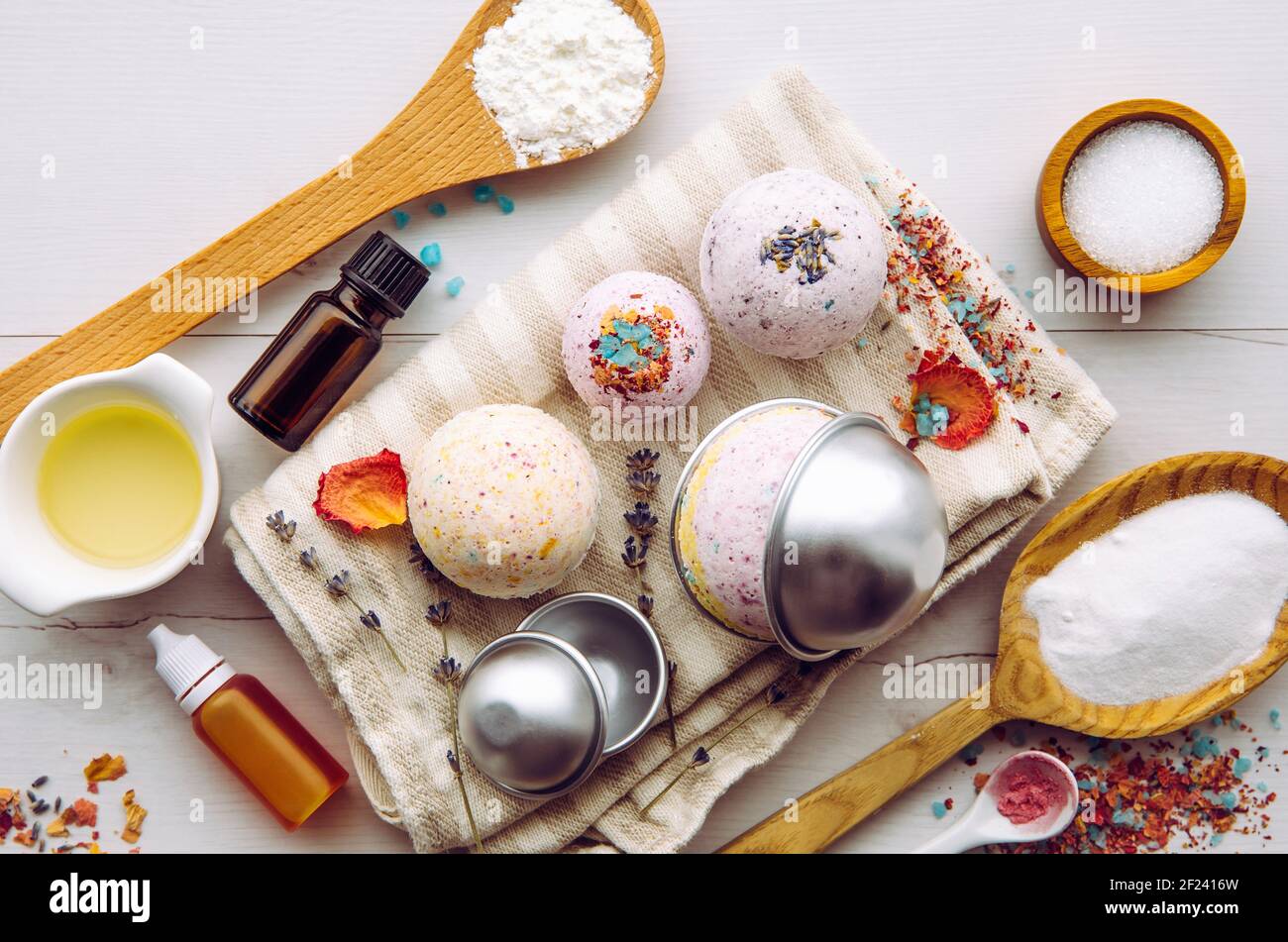 Making bath fizz bombs at home concept. All the ingredients on table on wood spoons: cornstarch, essential oil, dye, citric acid, baking soda. Stock Photo