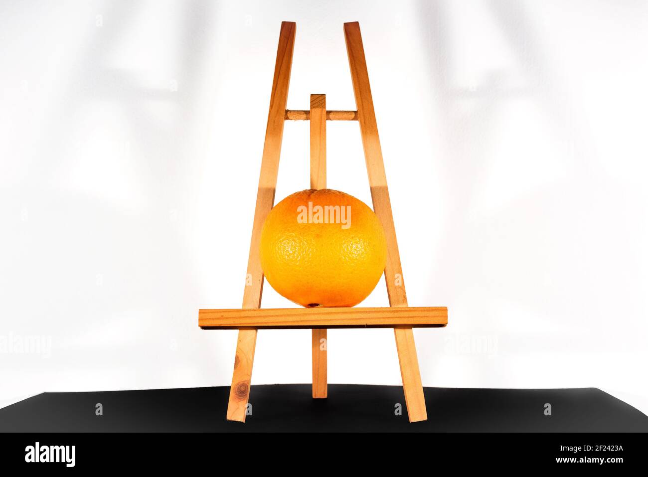 Portrait of an orange on an easel. Modern still life concept. Stock Photo