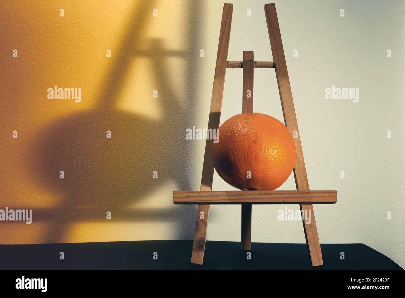 Portrait of an orange on an easel. Modern still life concept. Stock Photo